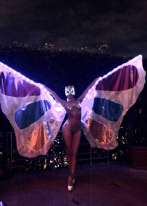 LED butterfly performer in a sparkling bodysuit and illuminated mask posing with glowing wings at a nighttime event in South Florida by Aura Entertainment.